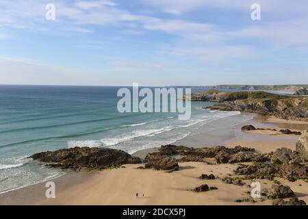 A panoramic view of a two people walking on the beach looking out over Watergate Bay in North Cornwall , South West Coast path Stock Photo