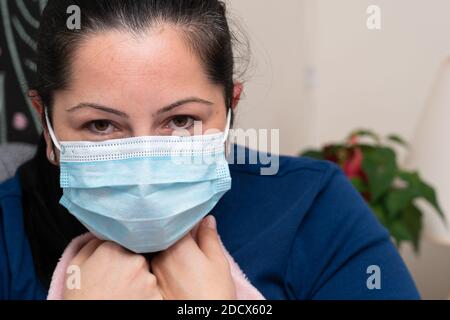 Close-up of flu or covid19 virus infection sick feeling unwell adult female model wearing disposable surgical or medical protective mask as influenza Stock Photo