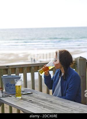 GREAT BRITAIN /Cornwall/ Newquay / Woman drinking a beer at Fistral Beach Bar and looking into the sea . Stock Photo