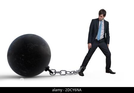 Young businessman has chained big metal ball to his leg. Isolated on white background. Stock Photo