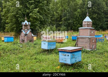 Perm, Russia - August 13, 2020: vintage hives in the form of temples among ordinary hives in a forest apiary Stock Photo