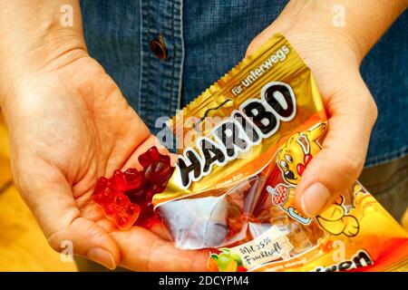 Tambov, Russian Federation - October 30, 2020 Woman pouring Haribo gummy Bears candy  from Haribo pack. Stock Photo