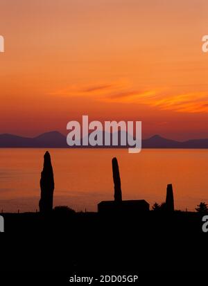 Ballochroy Bronze Age standing stones looking NNW across Gigha Sound just after the midsummer sun has set behind the Paps of Jura. Stock Photo