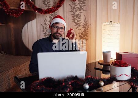 Virtual Christmas day house party. Man smiling wearing Santa hat Business video conferencing Online team meeting video conference calling from home. Stock Photo