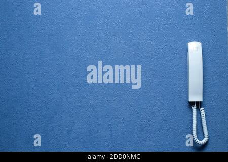 white intercom receiver on blue wall with copy space. Stock Photo