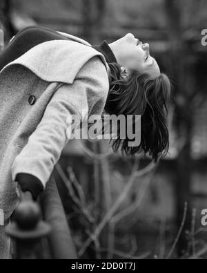 Brunette girl has bent back on the bridge in city in autumn. Plus size model. Black and white Stock Photo