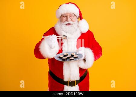 Portrait of his he nice cheerful white-haired Santa enjoying eating domestic gourmet sushi roll maki lunch oriental cuisine isolated bright vivid Stock Photo