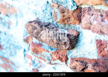 A brick wall with white mortar, with the bricks, standing out of the wall unevenly and broken Stock Photo