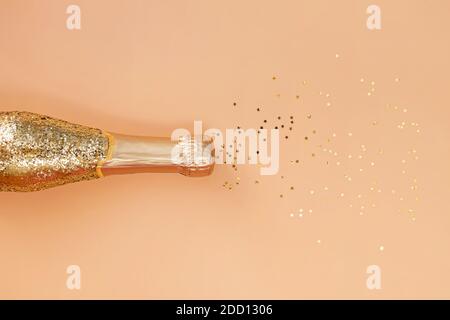 Gold glittering bottle of champagne and star shaped confetti. Stock Photo