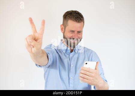 Handsome happy casual man making the victory sign while talking on the phone Stock Photo