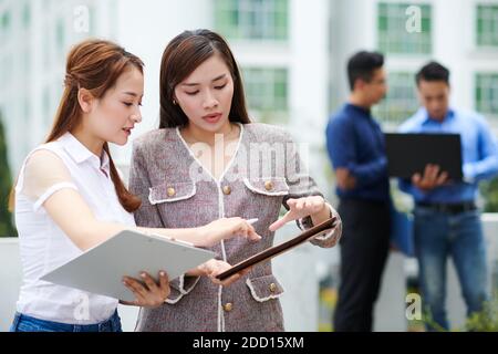 Young female entrepreneurs discussing data in financial documents at meeting Stock Photo