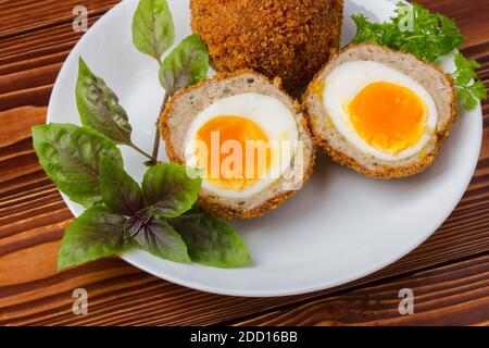 Cooked scottish eggs on white porcelain plate close up Stock Photo