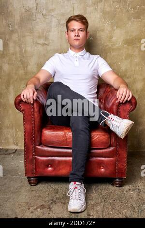 portrait of bossy caucasian man on leather chair sofa or couch, sit looking at camera, posing. Stock Photo