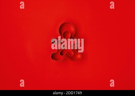 flat lay with gingerbread men cookie cutter on red background. Stock Photo