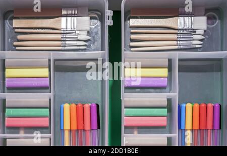 Plastic pencil cases with colored crayons, brushes and felt-tip pens. Stock Photo