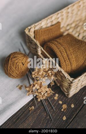 A pair of hand knitted socks in a basket,  knitting needles and yarn ball.  Background for handmade and slow homelife. Selective focus. Stock Photo