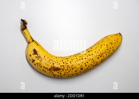 Overripe banana with black dots on white background shows healthy nutrition for vegetarians and vegans with dark spots as studio shot ingredient conta Stock Photo