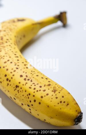 Overripe banana with black dots on white background shows healthy nutrition for vegetarians and vegans with dark spots as studio shot ingredient conta Stock Photo