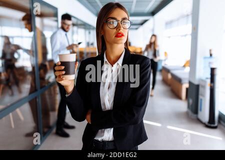 Business young woman walking down the corridor in the office drinking coffee during the break Stock Photo