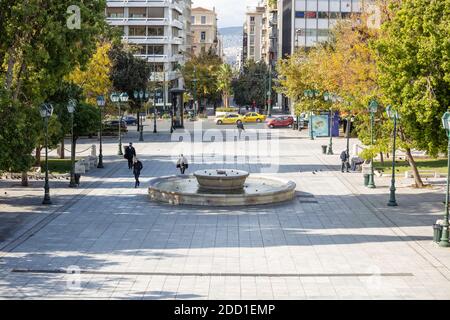 Athens Greece, November 19, 2020. A few people wearing COVID 19 protective face masks walking on Syntagma square, sunny day Stock Photo