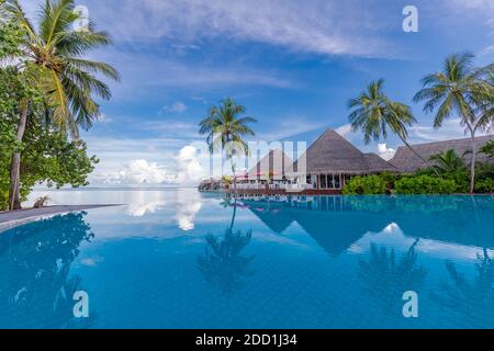 Beautiful luxury hotel pool resort beach, palm trees, loungers with umbrella. Infinity swimming pool, tropical beach landscape, seascape summer travel Stock Photo