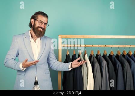 perfect design. tailor man has fashionable look. Elegant suits hang in row. Mens clothes on hanger. mature man looking for jacket. professional male sartor with jacket on hanger. presenting product. Stock Photo