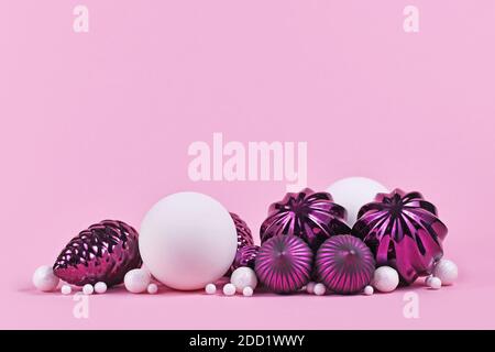 Christmas arrangement with purple and white tree ornament glass baubles on pink background with empty copy space Stock Photo