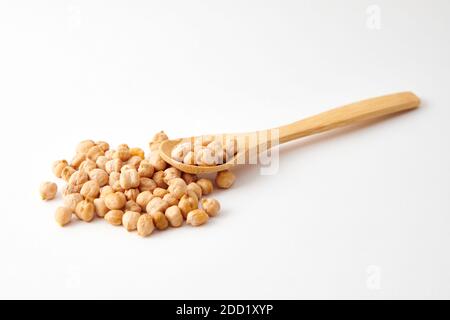 A pile of chickpeas on a wooden spoon and scattered on the white surface Stock Photo