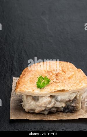 Homemade  flaky pasty with chicken and mushroom filling on black stone table Stock Photo