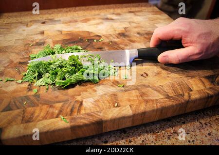 Closeup of a hand holding a knife cutting green mint Stock Photo