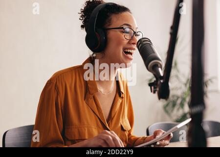 Young woman makes a podcast audio recording at home. Female enjoying while podcasting from home. Stock Photo