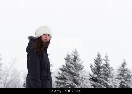 young adult, teen girl, walking outside in winter landscape weather, snow and frost on trees in background looking at camera MR Images of people with Stock Photo