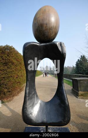 A sculpture by Joan Miro stands in the grounds of the Yorkshire Sculpture Park. A distant group of figures is framed by the sculptures contours. Stock Photo