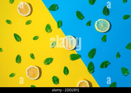 Multiple fresh leafs of peppermint on blue and yellow background with slices of lemons Stock Photo