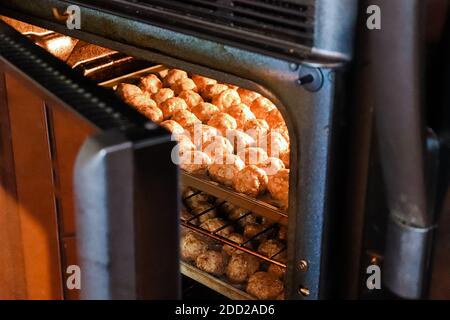 Peaking into an oven baking trays of meatballls Stock Photo