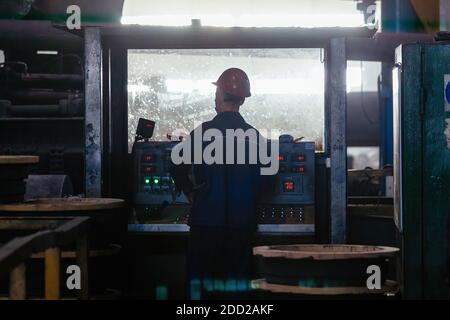 industrial worker operating CNC machinery in metallurgical factory. Stock Photo