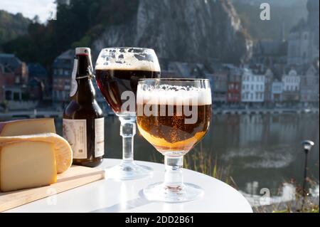 Drinking of dark and strong Belgian abbey beer with cheeses in sunny day with nice view on Maas river and town Dinant, Belgium Stock Photo