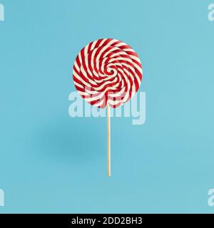 Colorful lolipop on blue background, wooden stick, red and white spiral, childhood sweets, Christmas concept Stock Photo