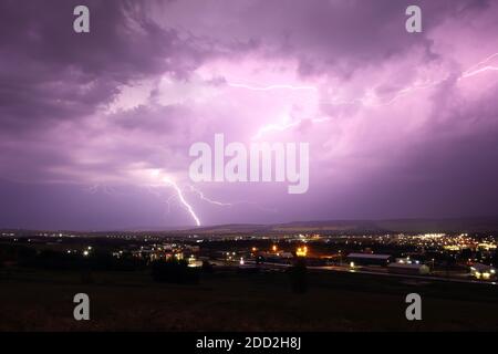Lightning strikes from stormy skies over cityscape. Stock Photo