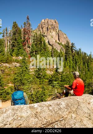 WA18466-00...WASHINGTON - Pacific Crest Trail hiker taking a break at the crest of the Cathedral Peak Saddle in the Alpine Lakes Wilderness area. Stock Photo