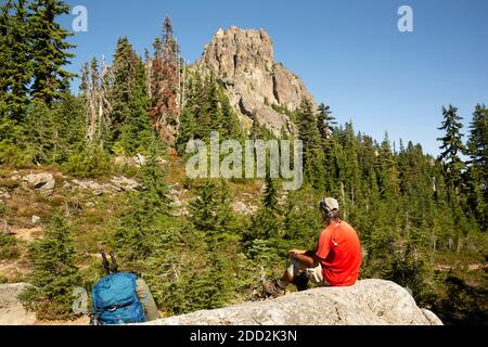 WA18467-00...WASHINGTON - Pacific Crest Trail hiker taking a break at the crest of the Cathedral Peak Saddle in the Alpine Lakes Wilderness area. Stock Photo
