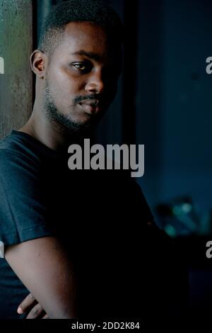 Sad african man standing in dark room. Depression and anxiety disorder concept Stock Photo