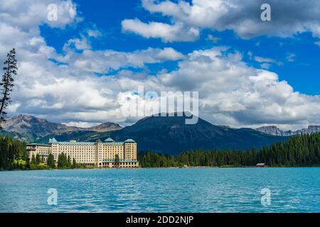 Fairmont Chateau Lake Louise in summer sunny day morning. Blue sky and white clouds reflected on the turquoise color lake water surface. Beautiful la Stock Photo