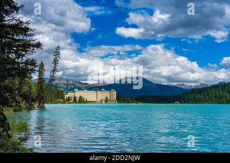 Fairmont Chateau Lake Louise in summer sunny day morning. Blue sky and white clouds reflected on the turquoise color lake water surface. Beautiful la Stock Photo