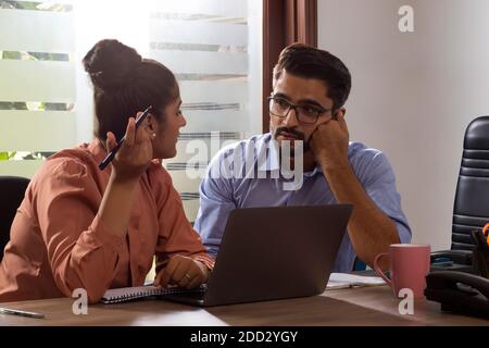 A YOUNG MAN AND WOMAN WORKING TOGETHER IN OFFICE Stock Photo