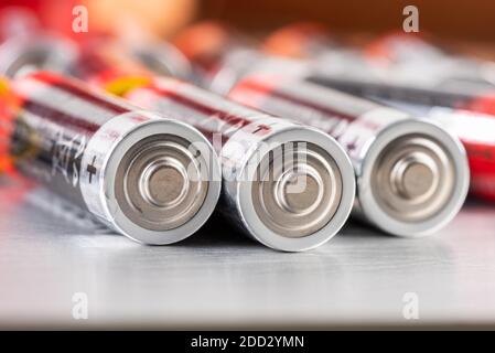 Macro of AA alkaline batteries lying on metal table with blurred energetic background Stock Photo
