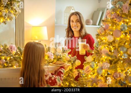 Girl holding a plate with fresh homemade pastries, her mom smiling Stock Photo