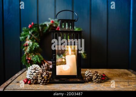 Vintage lantern with burning candle and fir branches on a wooden background Stock Photo