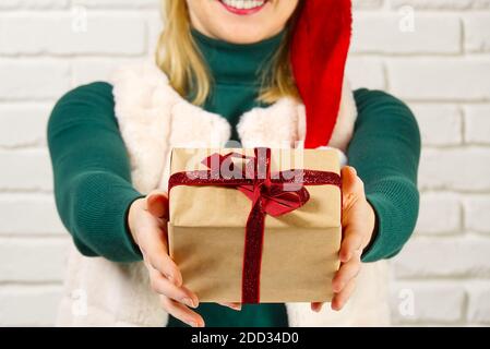 Female hands holding a small gift box wrapped in packing paper. To give and receive gifts from loved ones for christmas, valentines, birthday. Stock Photo