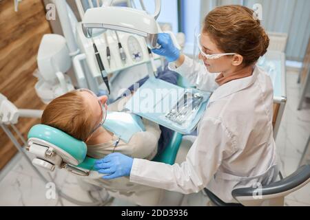 Dentist using medical instruments during dental procedure with patient at clinic Stock Photo